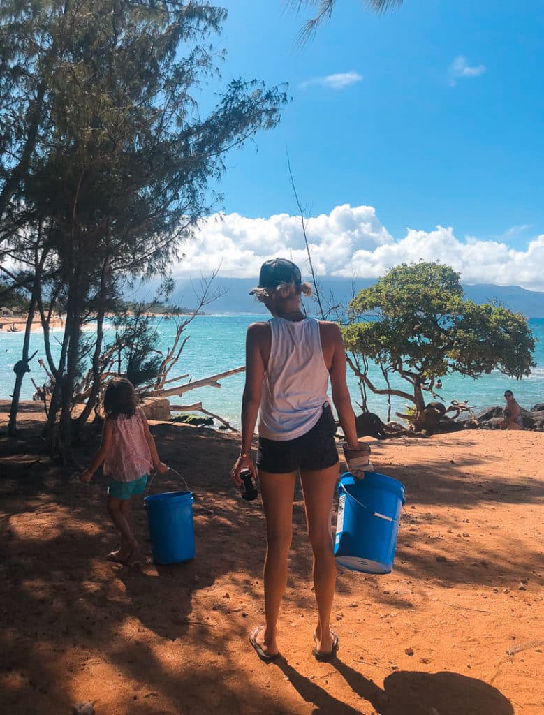 A mom and daughter holding buckets while volunteering in Hawaii. 