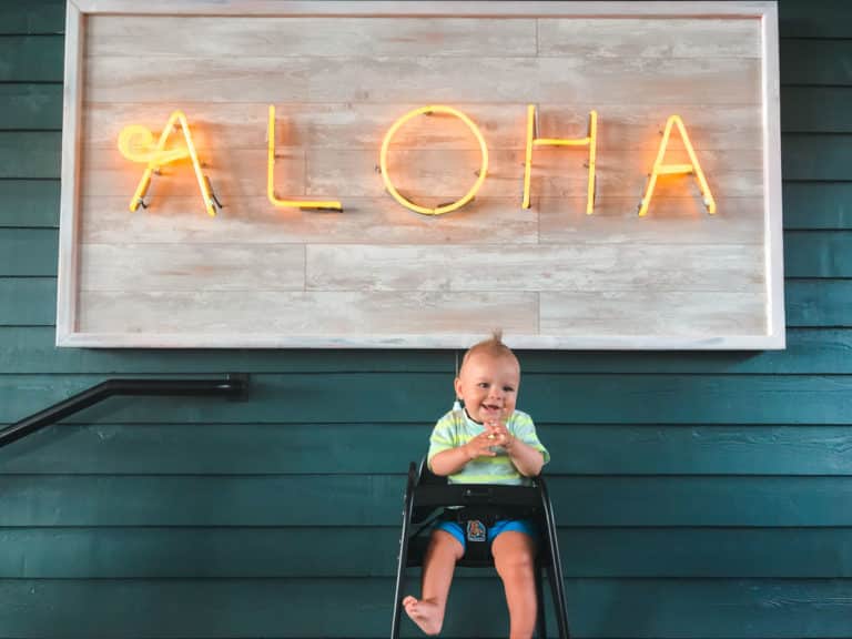 Baby in front of aloha sign at kid-friendly restaurant on Maui, Hawaii.