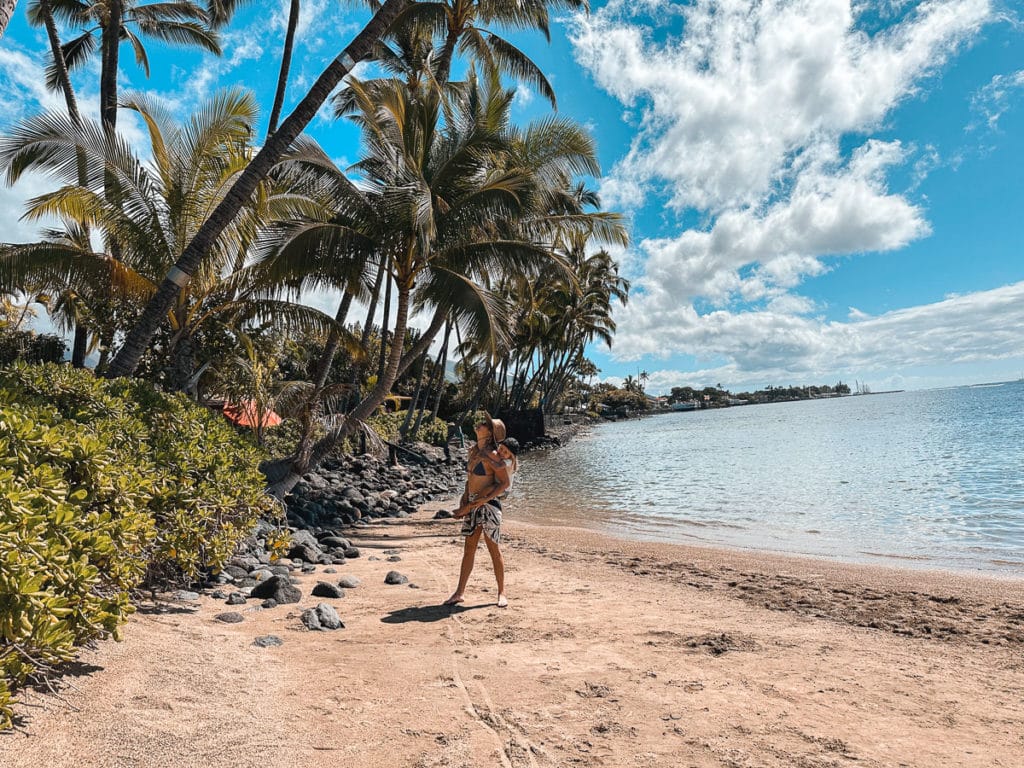 Mom with her kid on her shoulders at Baby Beach Lahaina, Maui.