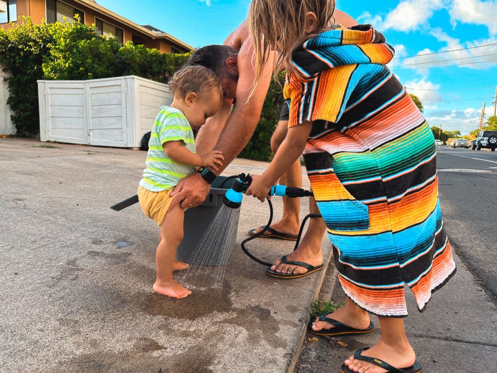 Dad rinsing off his kid's feet in Maui, Hawaii.