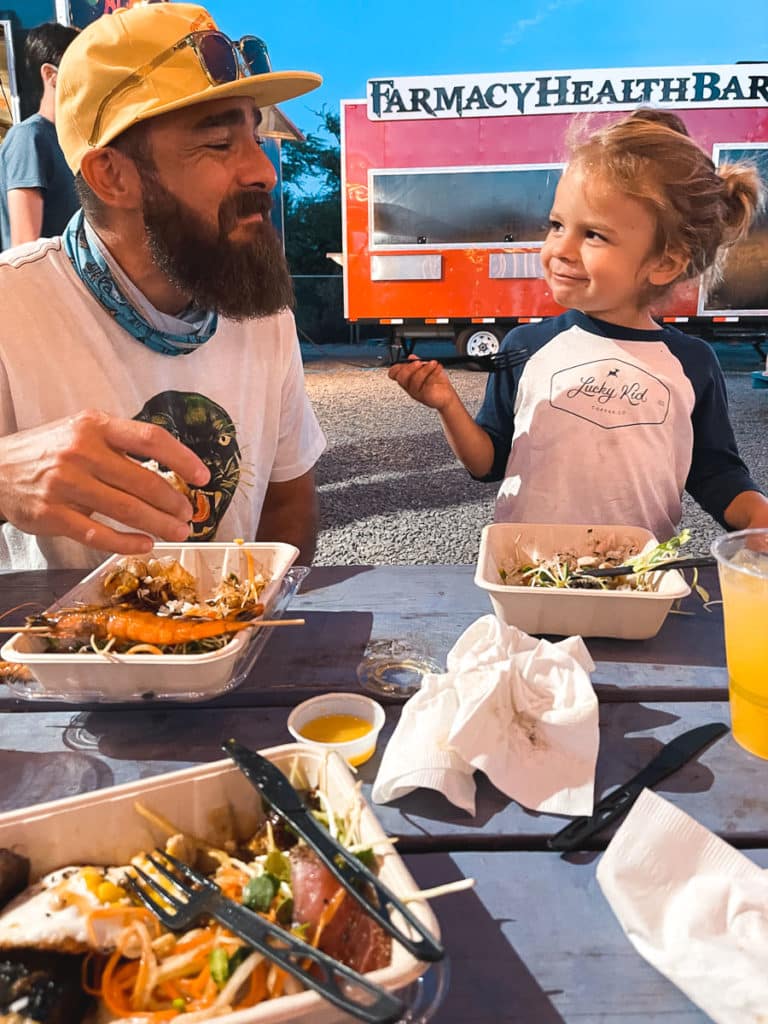 A toddler eating with his dad at a family-frieindly food truck on Maui.