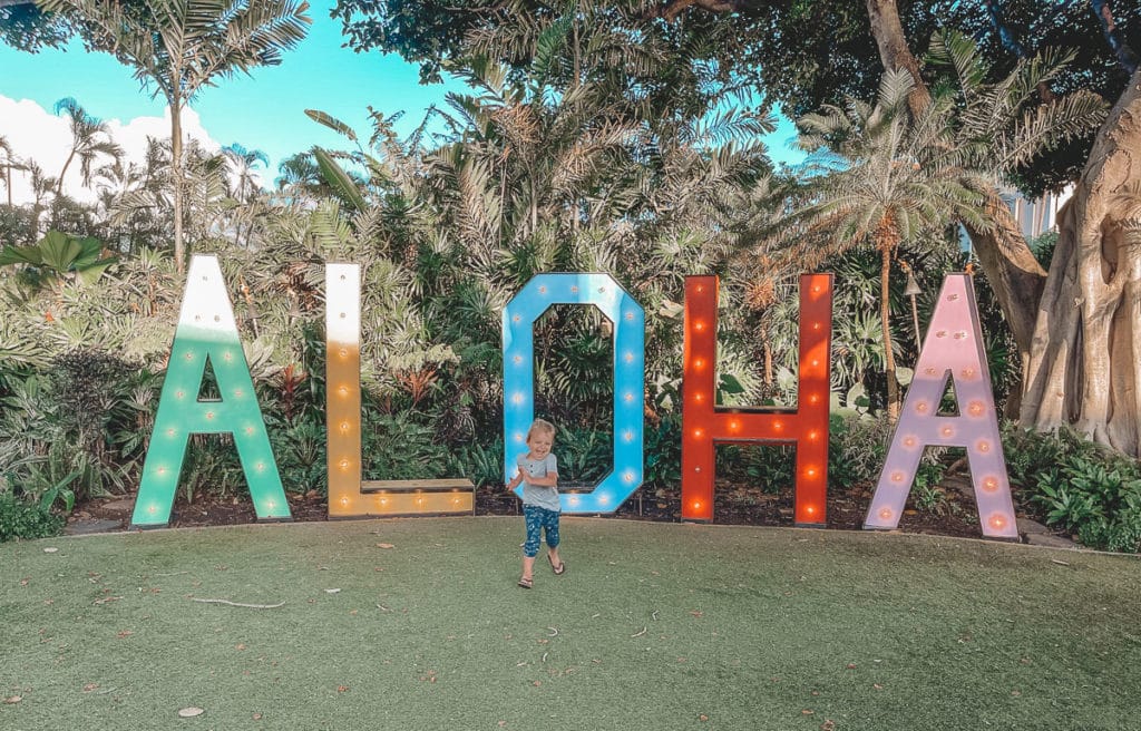 A young child running in front of a colorful Aloha sign at the Wailea Beach Resort in Maui, Hawaii. 