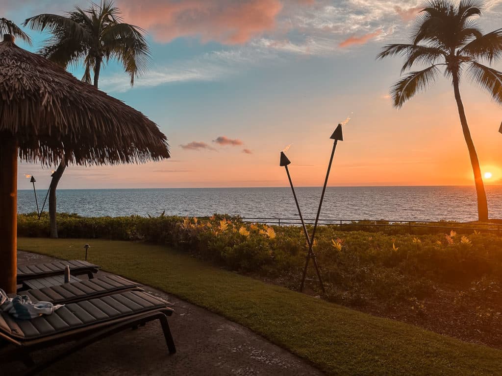 A view of the sun setting over the pacific ocean from Outrigger Hotel's pool deck on the Big Island of Hawaii. 