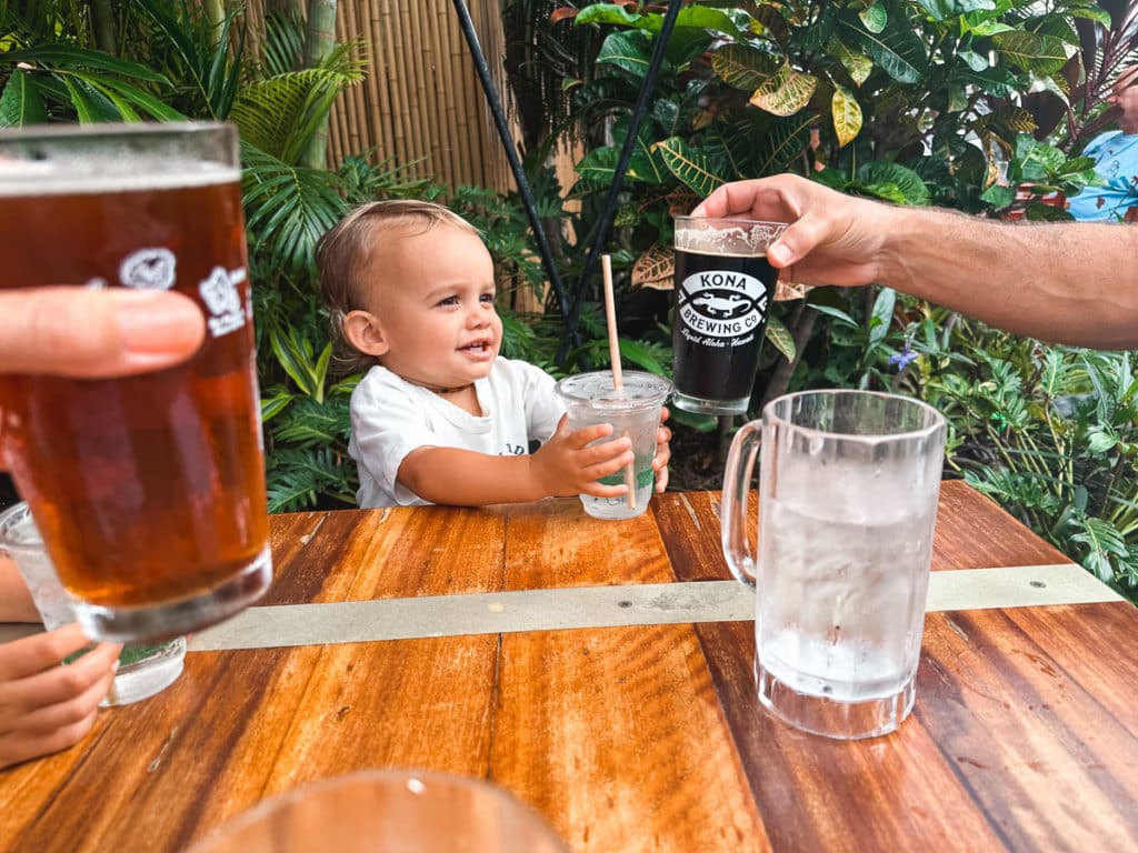 A baby cheersing a water cup with his family at Kona Brewing Company on the Big Island of Hawaii.