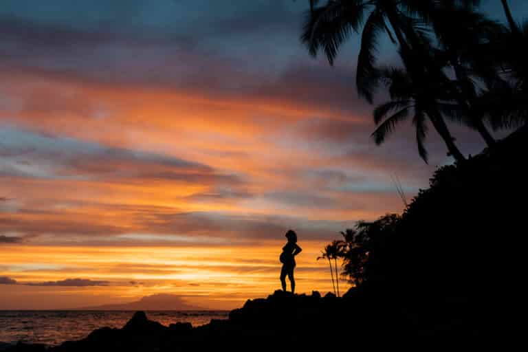 A silhouette of a pregnant woman and a vibrant Hawaii sunset.