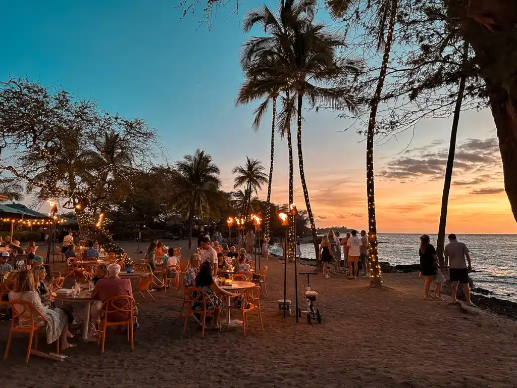 Outdoor dining with a view of sunset over the ocean at Lava Lava Beach Club on the Big Island of Hawaii. 