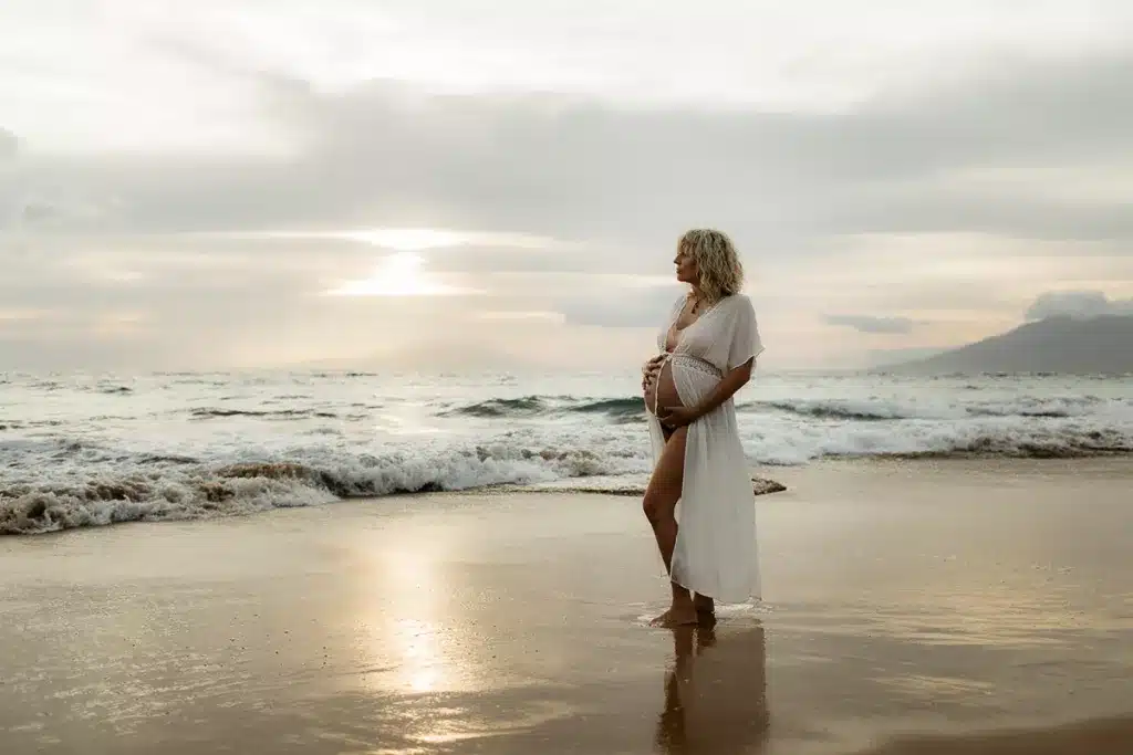 A pregnant woman staring out at the water on the island of Maui.