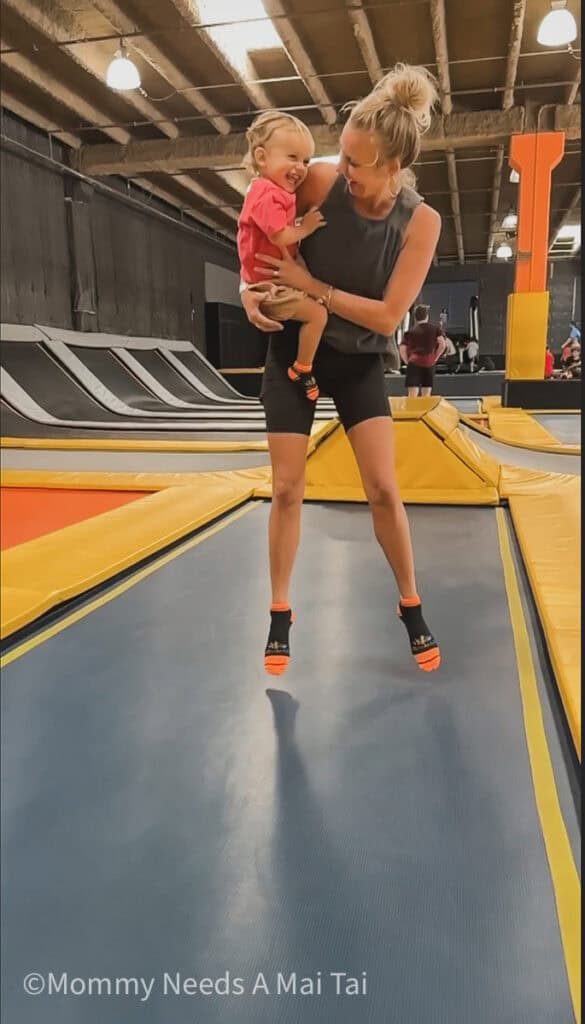 A mom holding her toddler while jumping in the air at Ultimate Air Maui in Hawaii.