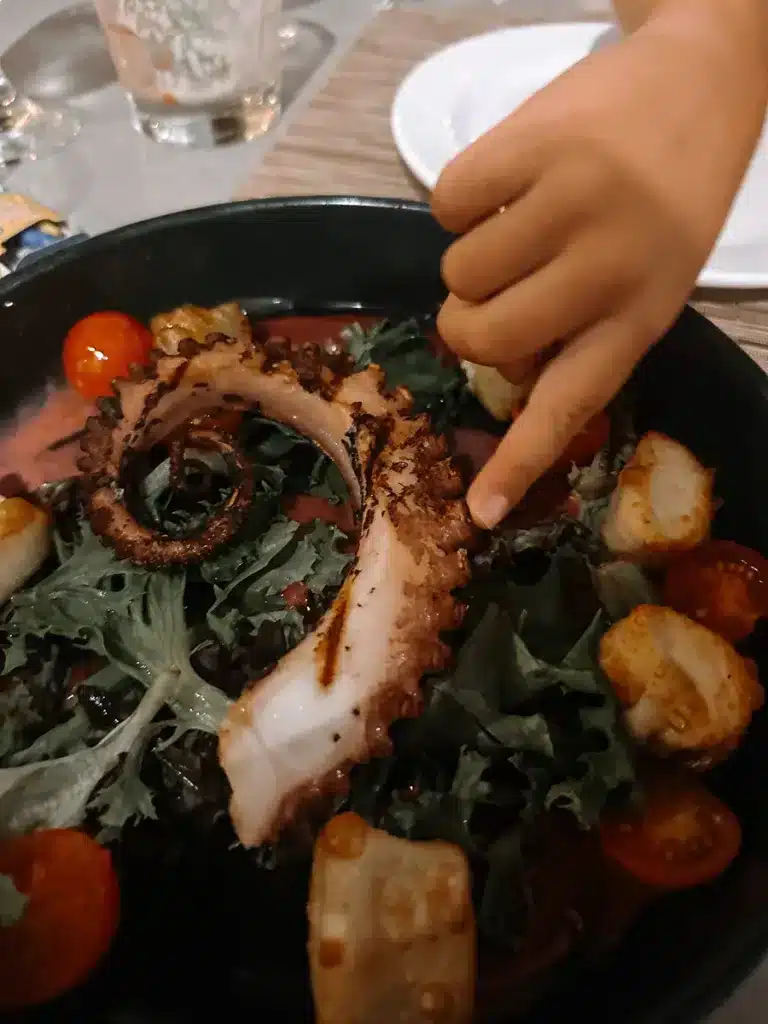 A boy touches a charred octopus tentacle at Nick's Seafood Restaurant in Maui, Hawaii. 