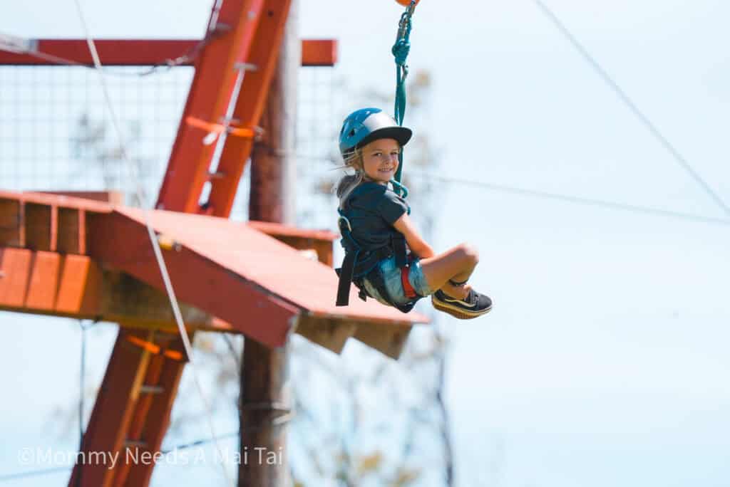 A young boy ziplining through the air at NorthShore zipline in Maui, Hawaii. 