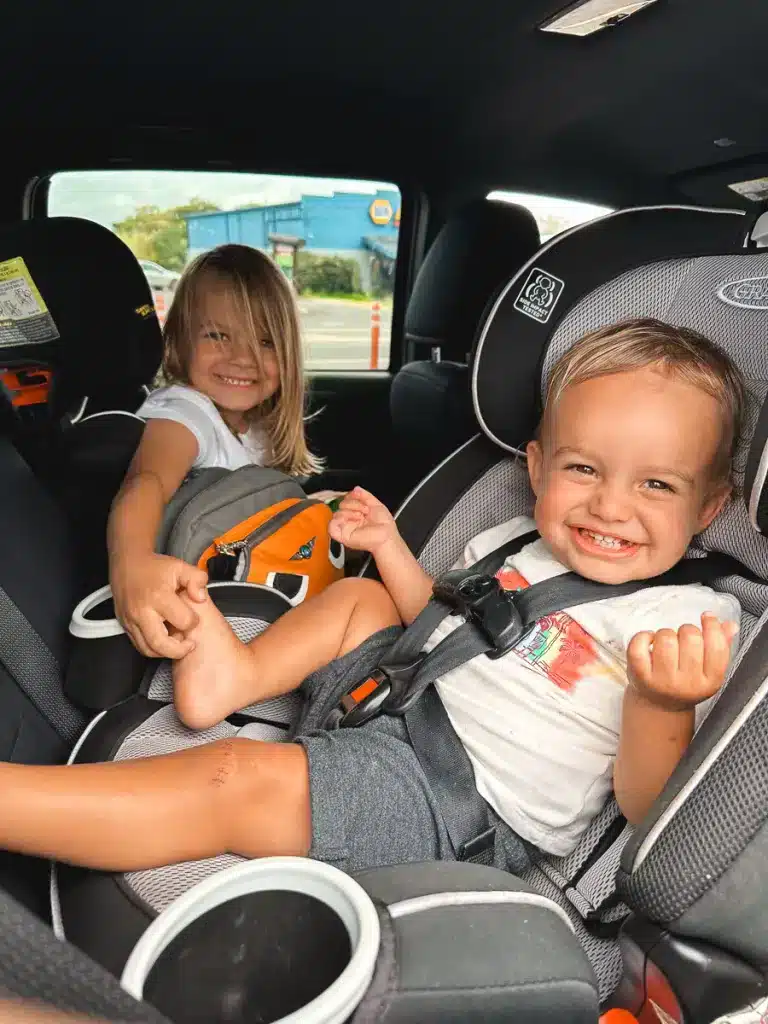 Two young boys in car seats laughing and looking happy on the Big Island of Hawaii.