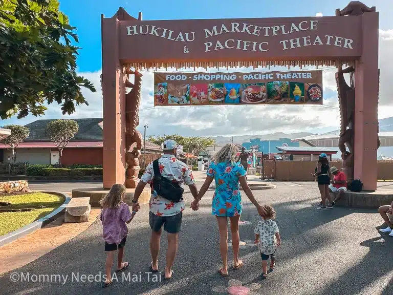 A family of four holding hands and walking at the Polynesian Cultural Center in Oahu, Hawaii.