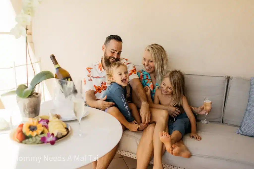 A family of four relaxing with a bottle of champagne at the Four Seasons on Oahu.