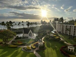 A view of a spanning resort, Wailea Seaside Chapel, lawn, palm trees, and ocean from above at the Grand Wailea Resort in Maui, Hawaii.