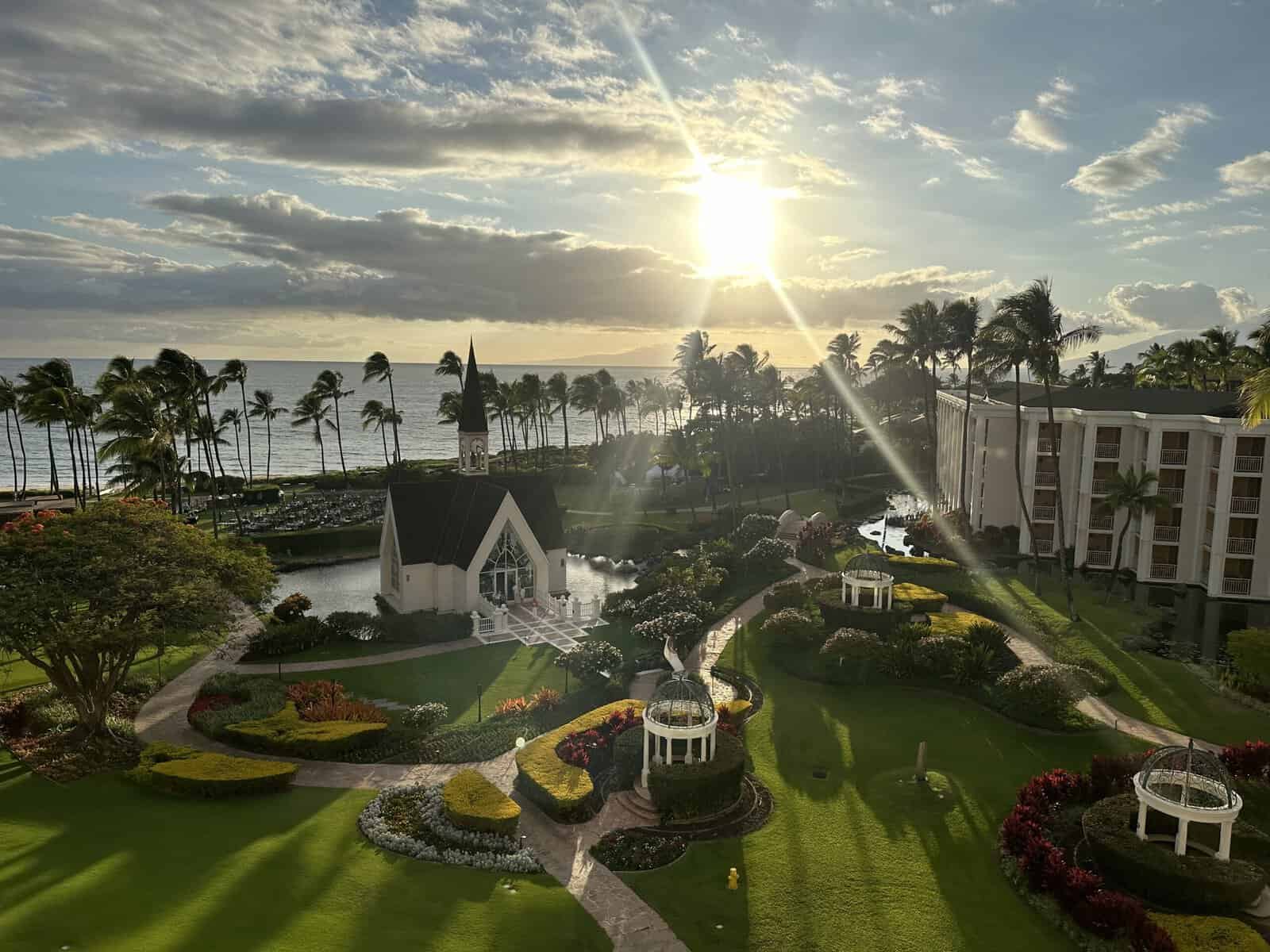 A view of a spanning resort, Wailea Seaside Chapel, lawn, palm trees, and ocean from above at the Grand Wailea Resort in Maui, Hawaii.