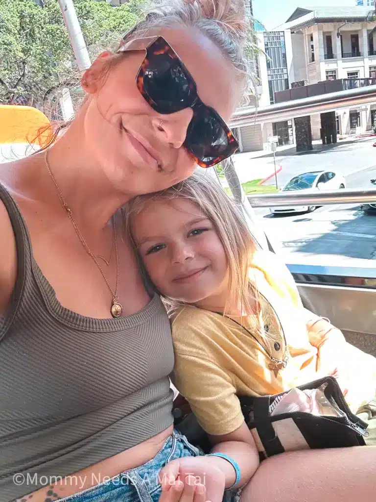 A mom and young son smiling while riding on a tour bus in Oahu. 