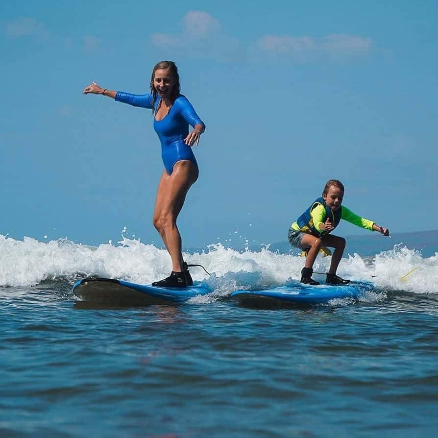 A mom and son smiling and surfing for the first time at Kalama Beach Park on Maui. 