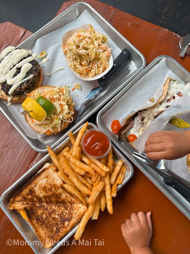 A little kid's hand grabbing for french fries and tacos from Kauai Beer Co on Kauai.