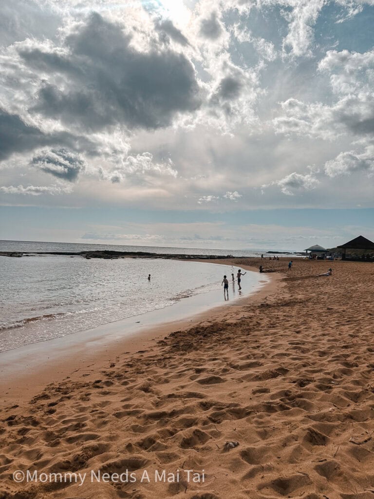 Kids running down the beach at Salt Pond Beach Park on Kauai. 