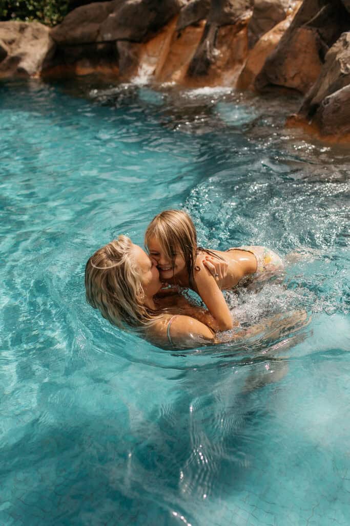 A mom and son swimming in blue pool water.